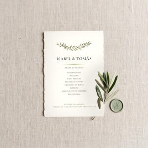 May include: A cream-colored wedding program with deckled edges featuring a green olive branch illustration, the text ISABEL & TOMÁS, and an order of service. A small green olive branch and a round green wax seal with a leaf imprint sit beside it.