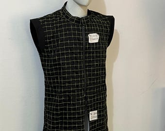 May include: A sleeveless black vest featuring a grid pattern of thin yellow lines, a high collar, and a full-length front zipper. Two white rectangular labels are attached to the front, each clearly displaying the text The DEAL DIGGER.
