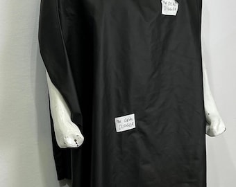 May include: A black salon cape draped over a white mannequin. The cape features two white rectangular labels, each printed with the text The DEAL DIGGER in black ink, positioned on the upper chest and the lower front section of the garment.