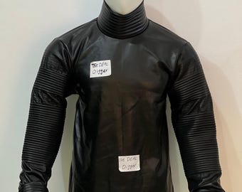 May include: A black long-sleeve shirt with a high mock neck collar, featuring ribbed textured detailing on the sleeves and cuffs. The shirt has two white rectangular labels attached to the front, each with the handwritten text The DEAL Digger.