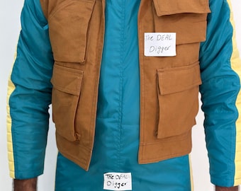 May include: A brown utility vest with four large front pockets worn over a teal and yellow jacket. The vest features a white paper tag with the text The DEAL Digger, and a matching tag is attached to the teal jacket below the vest.