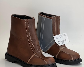 May include: A pair of brown ankle boots with black lug soles and white contrast stitching. The boots feature a grey panel on the outer side and a white tag attached to the front with the handwritten text The DEAL Digger in black ink.