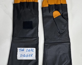 May include: A pair of long black gauntlet gloves featuring mustard yellow fingertips and thumb. The gloves have a black hook-and-loop fastener patch on the back of the hand and a white rectangular label with the text THE DEAL DIGGER attached.