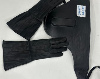 May include: A pair of black leather gloves with stitched detailing and a black leather chest piece featuring adjustable straps and a white rectangular tag with the handwritten text THE DEAL DIGGER in blue ink.