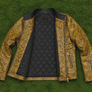 Puede incluir: Una chaqueta con estampado de piel de serpiente en color amarillo mostaza y negro con forro interior acolchado negro. La chaqueta cuenta con cuello alzado, cierre de cremallera frontal, dos bolsillos con cremallera y pu&ntilde;os con cremallera.