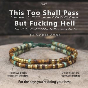 May include: A double-strand bracelet featuring brown tiger eye beads and metallic golden spacers arranged in a Morse code pattern. The text "This Too Shall Pass But Fucking Hell IN MORSE CODE" is displayed above, with labels identifying the beads.