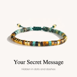 May include: A beaded bracelet featuring alternating cylindrical beads in gold, brown tiger eye, and turquoise stone, with a dark green adjustable cord closure. The text below reads: Your Secret Message, Hidden in dots and dashes.