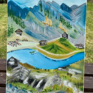 May include: An acrylic painting on canvas depicting a mountainous landscape with a winding blue river, green grassy hills, and several small dark-roofed cabins. The background features jagged blue and grey mountain peaks under a light blue sky.