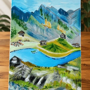 May include: An acrylic painting on canvas depicting a mountainous landscape with a bright blue river winding through green hills. Several small houses are scattered across the terrain, with textured brushstrokes in shades of blue, green, and yellow.