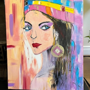 Peut inclure: Une peinture sur toile repr&eacute;sentant le portrait d'une personne aux longs cheveux fonc&eacute;s, portant un bandeau color&eacute; dans des tons rose, jaune et bleu. Le sujet a des yeux bleu vif, du fard &agrave; paupi&egrave;res violet, des l&egrave;vres rouges et une grande boucle d'oreille circulaire.