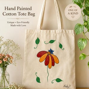 May include: A cream-colored cotton tote bag featuring a hand-painted design of a large flower with red and orange petals, a blue butterfly on top, and scattered green leaves. The text "Hand Painted Cotton Tote Bag" and "ONE OF A KIND" appear.