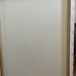 Peut inclure: Le dos d'une toile rectangulaire tendue sur un cadre en bois. La toile blanche est fix&eacute;e par des agrafes m&eacute;talliques le long des bords en bois. Le texte &eacute;crit sur le cadre en bois inf&eacute;rieur indique : PRETTY GIRL, Junie '25, 40.6 x 50.8 cm.
