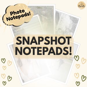 May include: A collection of rectangular paper notepads featuring printed photographs as backgrounds. The notepads include lined and grid layouts with the text "Notes" and "SNAPSHOT NOTEPADS!" and "Photo Notepads!" visible. Small green and tan heart icons decorate the edges.