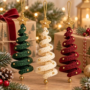 Könnte beinhalten: Drei spiralförmige Weihnachtsbaumschmuck-Anhänger aus gehäkeltem Garn in Dunkelgrün, Creme und Dunkelrot. Jeder Anhänger hat einen goldenen Stern mit einer kleinen weißen Perle an der Spitze, goldene Perlen entlang der Spirale und eine Goldglocke.