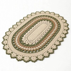 May include: An oval-shaped crochet doily featuring concentric rings of cream, tan, and olive green yarn. The design includes a central solid oval section surrounded by intricate, lacy, scalloped borders that create a decorative, textured edge.