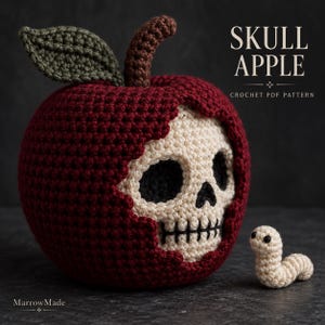 May include: A dark red crocheted apple with a beige skull face emerging from the center, featuring a brown stem and olive green leaf. Beside it sits a small beige crocheted worm. Text reads SKULL APPLE CROCHET PDF PATTERN and MarrowMade.