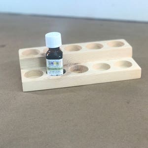 May include: Wooden essential oil rack with 10 slots, two tiers, and a small bottle of "Citronella Java" essential oil in the centre slot.