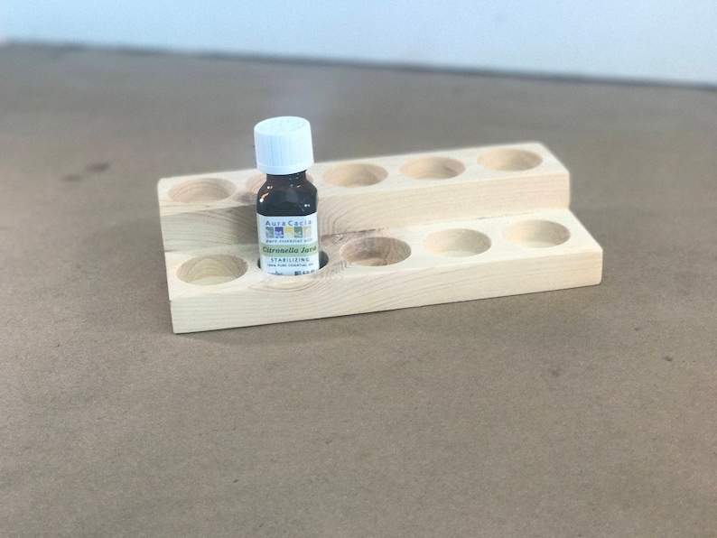 May include: Wooden essential oil rack with 10 slots, two tiers, and a small bottle of "Citronella Java" essential oil in the centre slot.