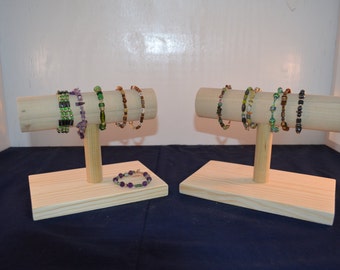 May include: Two wooden bracelet display stands with multiple colorful beaded bracelets. The stands are made of natural wood and have a simple design.
