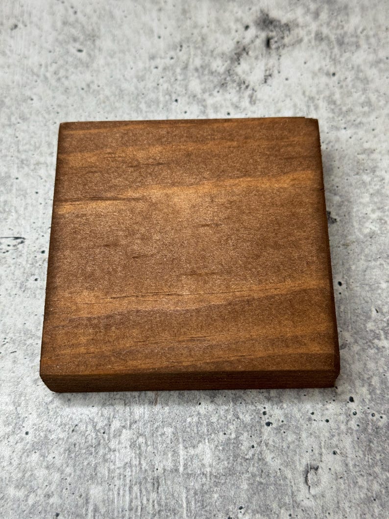 May include: A square piece of wood with a smooth, dark brown finish. The wood has a natural grain pattern.
