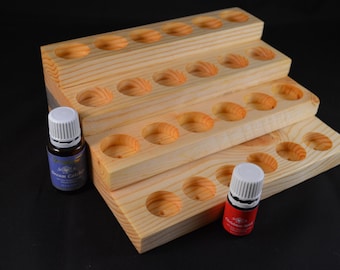 May include: Wooden essential oil storage rack with three tiers. Each tier has multiple round holes for storing essential oil bottles. Two essential oil bottles are visible, one with a blue label and the other with a red label.
