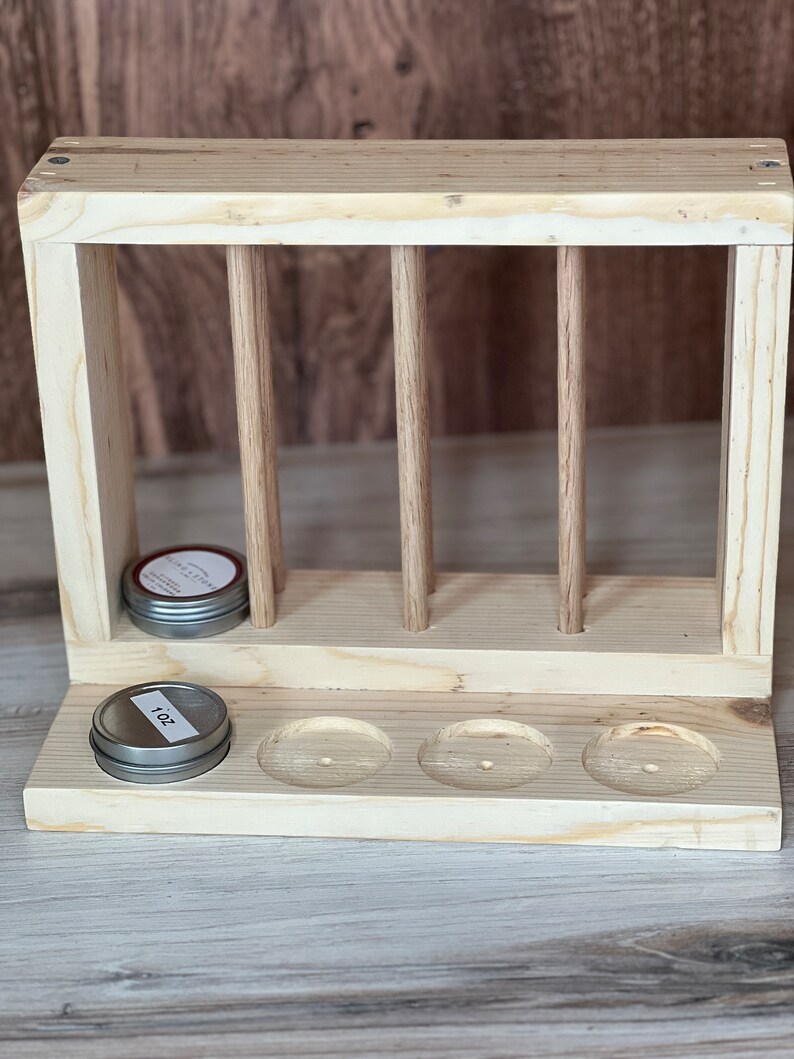 May include: Wooden stand with four vertical dowels and three round cutouts. The stand has two silver tins with labels that read "1 oz" and "Natural Citrus".
