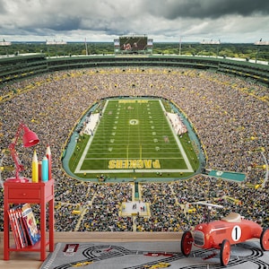 May include: A wall mural depicting a crowded football stadium with a green field, featuring a red side table with a red lamp, pencils, and books, a red signpost with directional arrows, and a red toy race car on a grey track rug.