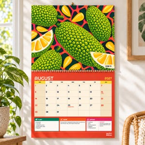 May include: A 2027 wall calendar for August featuring a vibrant illustration of green, bumpy jackfruit and yellow fruit segments against a red background. The calendar grid displays dates from 1 to 31, with text sections for plant, prune, and harvest tasks.