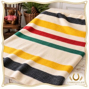 May include: A thick, cream-colored wool blanket featuring a repeating pattern of wide horizontal stripes in dark charcoal, golden yellow, bright red, and forest green. The textured fabric has a soft, fuzzy appearance with visible woven fibers.