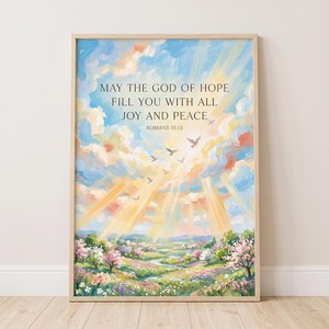 Könnte beinhalten: Ein gerahmter Kunstdruck mit einer gemalten Landschaft, einem lebendigen Himmel, Sonnenstrahlen und Vögeln. Der Text lautet: MAY THE GOD OF HOPE FILL YOU WITH ALL JOY AND PEACE ROMANS 15:13. Die Szene zeigt eine bunte Wiese mit blühenden Bäumen.