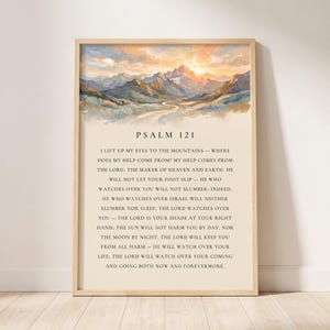 May include: A vertical wall art print in a light wood frame featuring an oil painting of a mountain landscape at sunrise above the text of Psalm 121. The text is printed in black on a cream background, detailing the verses in English.