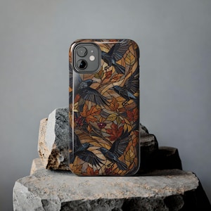 May include: A rectangular smartphone case featuring a stained glass style design. The pattern displays multiple black crows in flight amidst autumn leaves in shades of orange, yellow, and brown, with small clusters of red berries throughout the scene.