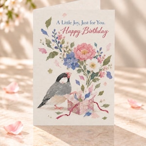 May include: A greeting card featuring a watercolour illustration of a Java sparrow standing next to a small floral gift box. Above the bird and flowers, the text reads A Little Joy, Just for You. Happy Birthday in blue and red script.