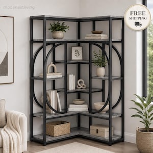 May include: A corner bookshelf featuring a black metal frame with circular side accents and grey wood-grain shelves. The unit is organised with various books, decorative bowls, a small potted plant, a woven basket, and a rectangular storage box.