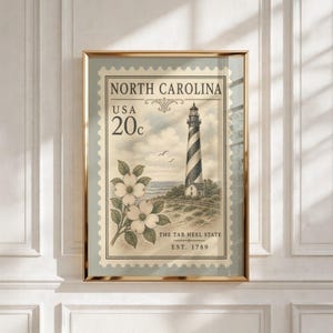 Peut inclure: Une impression d'art encadrée représentant un timbre-poste vintage de Caroline du Nord. Le timbre montre un phare rayé, des fleurs de cornouiller et le texte North Carolina, USA 20c, The Tar Heel State et Est. 1789 en encre noire.