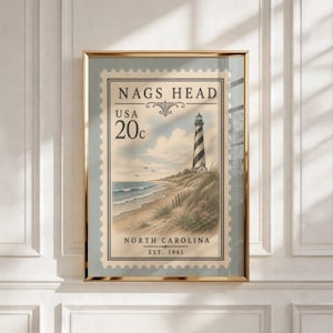 Puede incluir: Una impresión artística enmarcada con un diseño de sello postal de estilo vintage del faro de Nags Head en Carolina del Norte. La ilustración muestra un faro a rayas en una playa de arena con olas, el texto dice NAGS HEAD USA 20c.