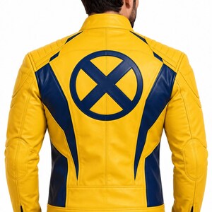 Puede incluir: Una chaqueta de cuero amarilla y azul marino con un prominente logotipo circular de X-Men en azul marino en la espalda. La chaqueta incluye un cuello alto, detalles acolchados en los hombros y paneles verticales azul marino en los lados.
