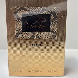 May include: A rectangular gold perfume box with a textured diamond pattern. A central black rectangular label features a brown and beige snakeskin print, the text "HAWAS" in gold, and Arabic script. The text "ELIXIR", "100 ML", and "3.38 FL. OZ" are printed.