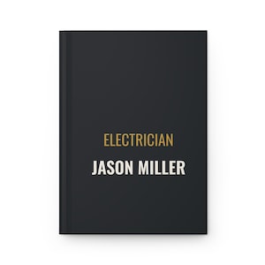 May include: A black hardcover notebook featuring the word ELECTRICIAN printed in gold text above the name JASON MILLER in white capital letters centered on the front cover. The notebook has a clean, solid black background and a vertical spine.