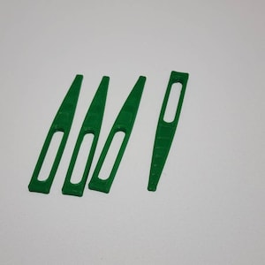 May include: Four green plastic knitting needles with a small hole in the center of each needle.