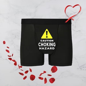 May include: Black boxer shorts with a yellow warning sign that reads "Caution Choking Hazard".
