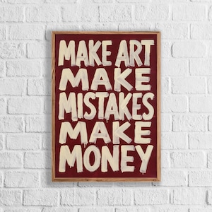 May include: A rectangular framed wall art piece featuring a deep maroon background with the text "MAKE ART MAKE MISTAKES MAKE MONEY" painted in large, bold, off-white brushstroke lettering that appears to have slight paint drips.