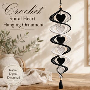Könnte beinhalten: Ein hängendes Spiralornament mit abwechselnd schwarzen und weißen gehäkelten Herzen. Die Struktur ist an einer schwarzen Schnur mit einer Holzperle oben und einer schwarzen Quaste unten befestigt. Der Text lautet: Crochet Spiral Heart Hanging Ornament und Instant Digital Download.