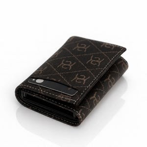 May include: A dark brown tri-fold wallet featuring a repeating light brown monogram pattern and a diamond-stitched design. A black credit card with a silver circular accent is partially inserted into the front exterior slot of the wallet.
