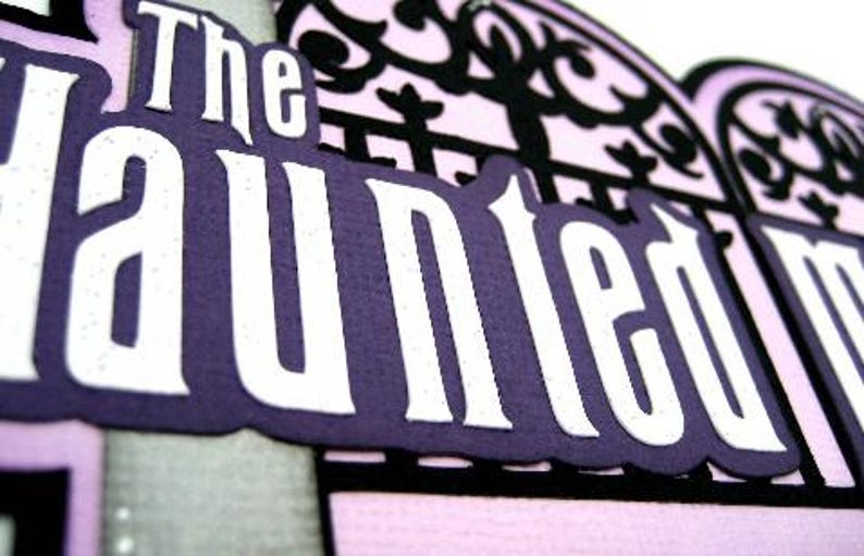 May include: The Haunted Mansion sign with white lettering on a purple background. The sign is framed by a black, ornate, gate-like design.