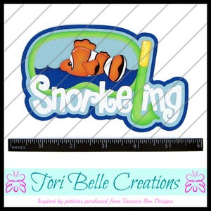 May include: A blue and green paper craft with the word "Snorkeling" in white letters. A cartoon orange and black clownfish swims in the water. The craft is approximately 5 inches wide.