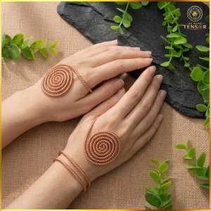 May include: A copper-colored metal hand ornament featuring a spiral design on the back of the hand connected to a double-strand wrist bracelet. The piece is constructed from twisted wire, creating a textured, coiled appearance on both hands.