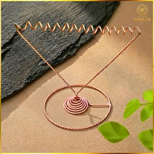 May include: A copper-colored metal display stand featuring a circular base, a central conical spiral coil, and a triangular frame topped with a horizontal spiral wire. The structure is constructed from twisted and smooth copper-toned wire.