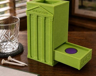 May include: A lime green 3D printed dice tower shaped like a classical building with columns and a pediment. The word MULLIGANS is embossed on the front pediment and the side of the extended tray. A single purple circular token sits in the tray.