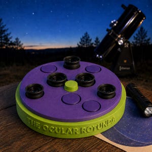 Könnte beinhalten: Ein runder Zubehörhalter aus lindgrünem und violettem Kunststoff mit der Aufschrift THE OCULAR ROTUNDA, ausgestattet mit vier schwarzen Teleskopokularen auf der Oberseite, einem zentralen lindgrünen Knopf und mehreren leeren runden Steckplätzen.